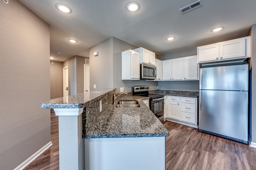 A kitchen with granite countertops and stainless steel appliances.
