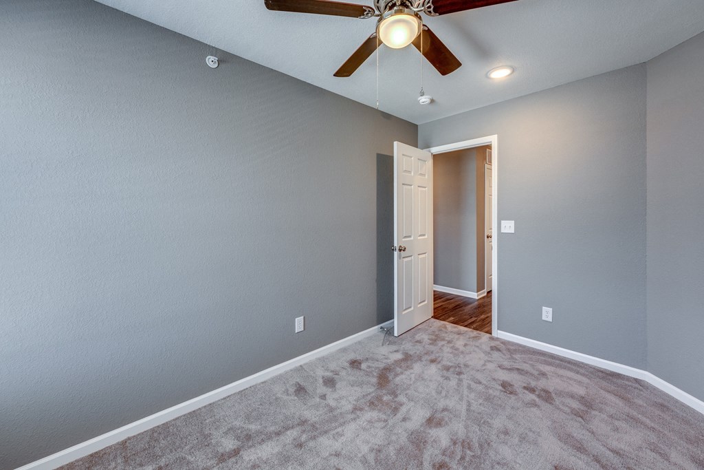 A room with a ceiling fan and a door.