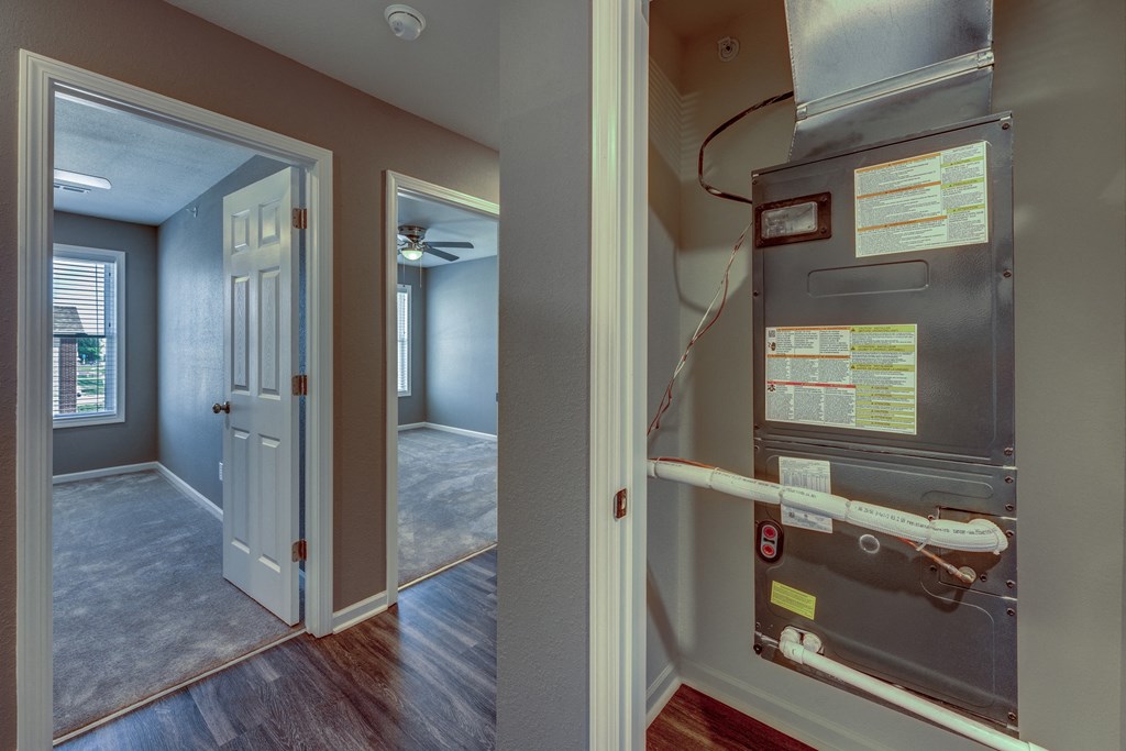 A room with a doorway leading to another room and a furnace on the wall.