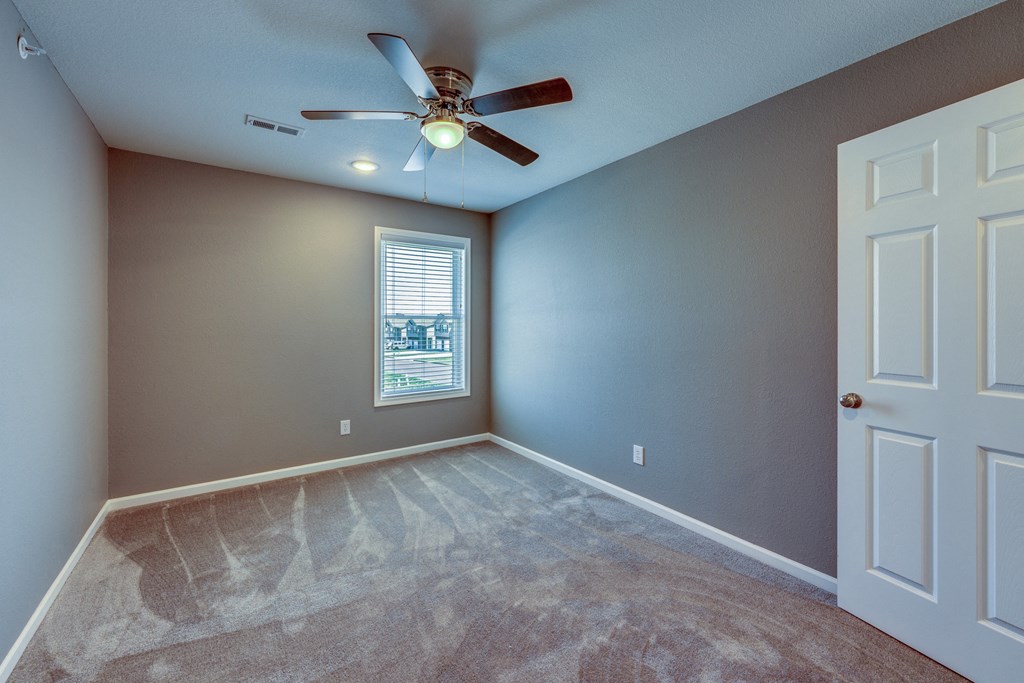 A room with a ceiling fan and a window.