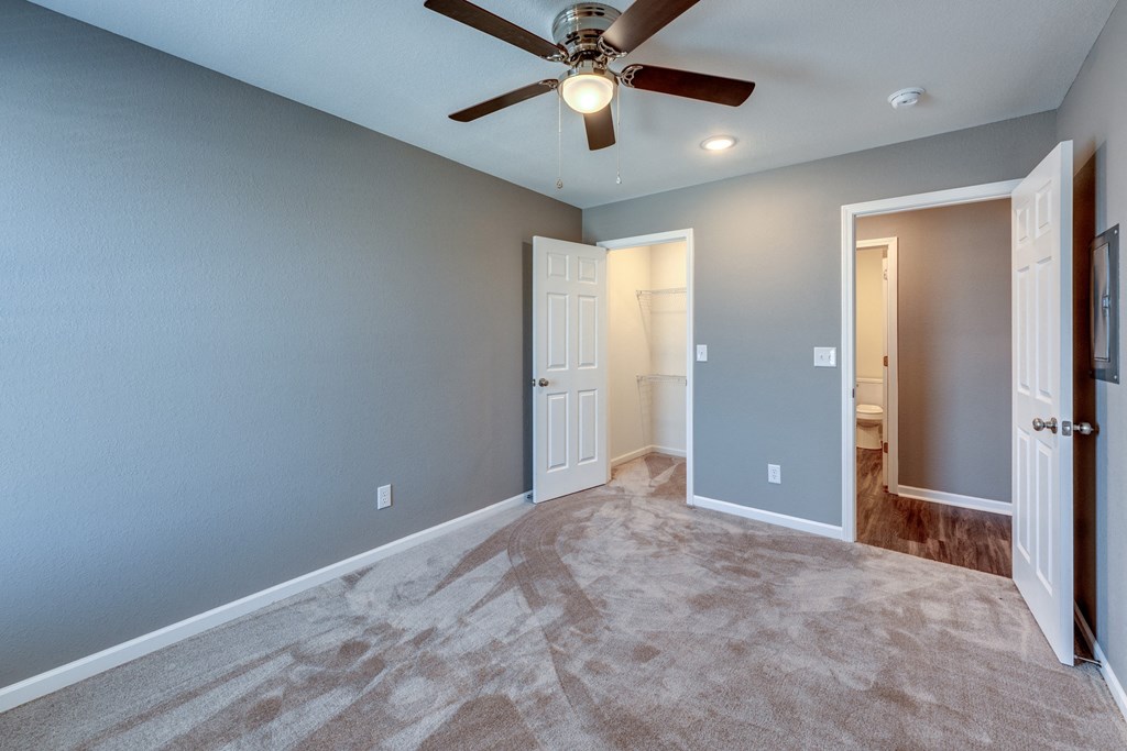 A room with a ceiling fan and carpeted floor.
