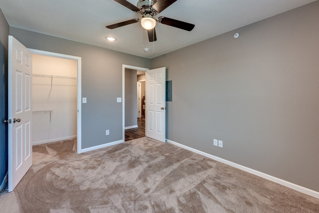 A room with a ceiling fan and carpeted floor.