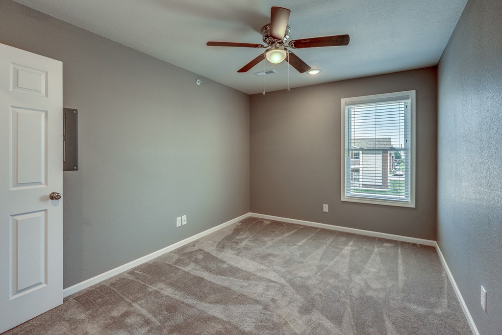 A room with a ceiling fan and a window with blinds.