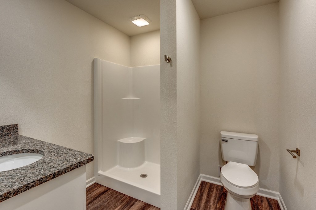 A white toilet is in a small bathroom with a walk-in shower.