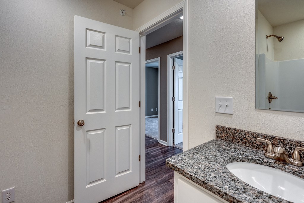A white door is in a bathroom with a granite counter top.