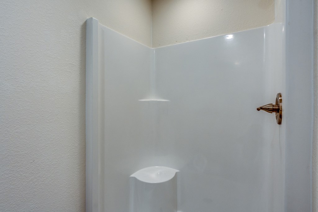 A white door with a brass handle and a white light on the wall.