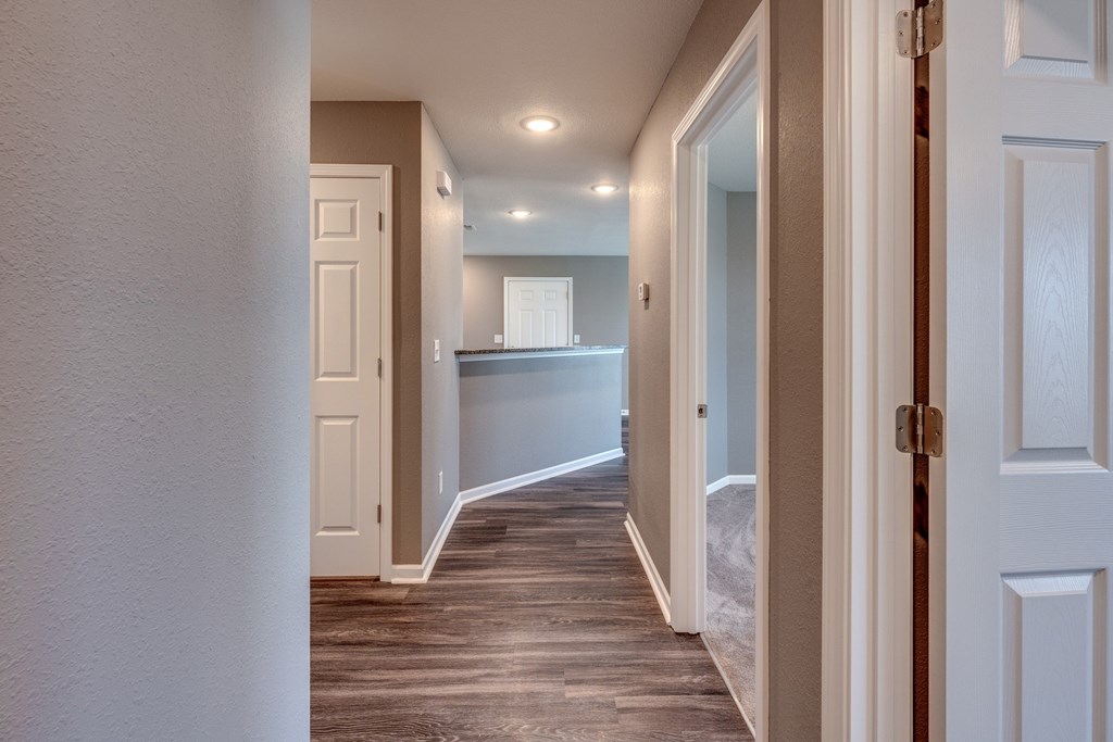 A hallway with a white door on the right and a brown door on the left.