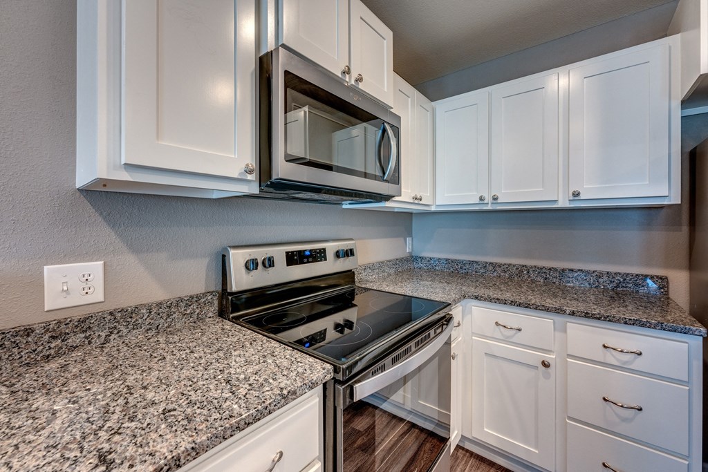 A kitchen with granite countertops and white cabinets.
