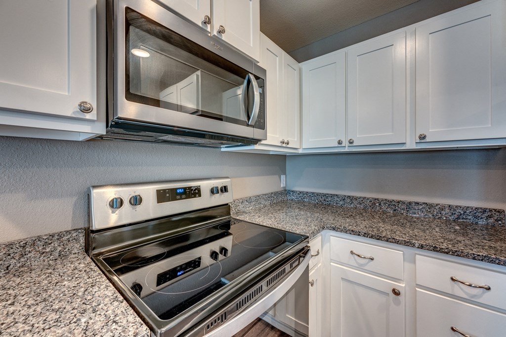 A modern kitchen with a stainless steel oven and microwave above it.
