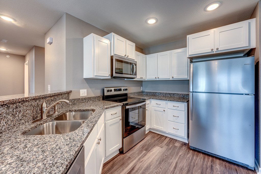 A modern kitchen with white cabinets and stainless steel appliances.