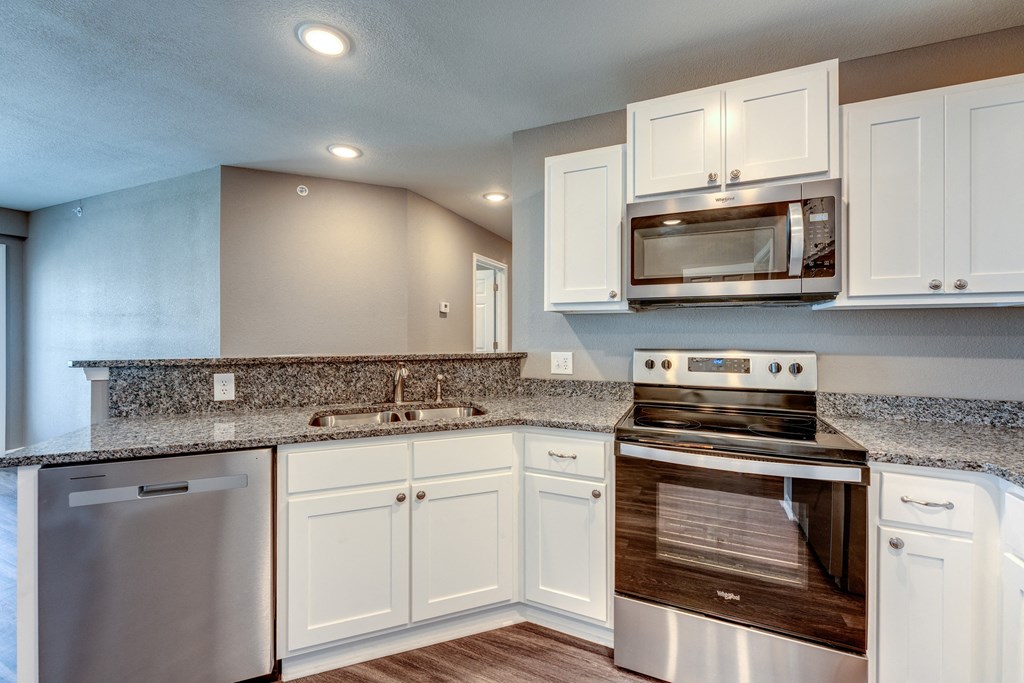 A modern kitchen with white cabinets and stainless steel appliances.