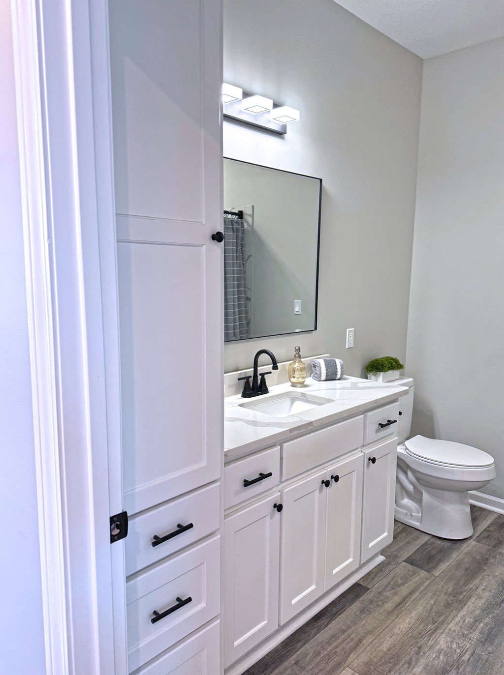 A white bathroom with a toilet, sink, and mirror.