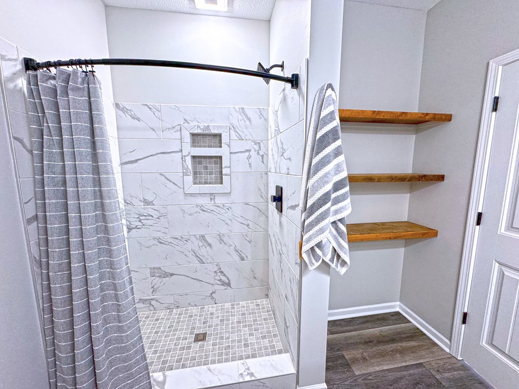 A bathroom with a marble tile shower and a towel hanging on a rack.