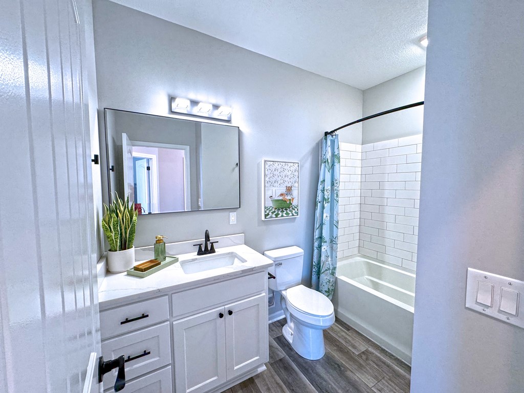 A white bathroom with a toilet, sink, and mirror.
