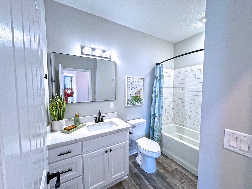 A white bathroom with a toilet, sink, and mirror.