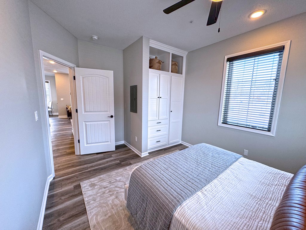 A bedroom with a bed, dresser, and a ceiling fan.
