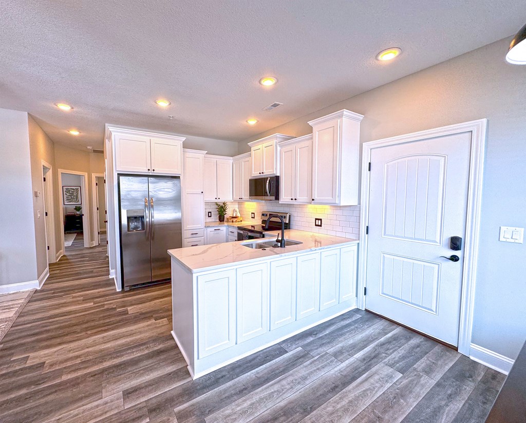 A kitchen with white cabinets and a refrigerator.