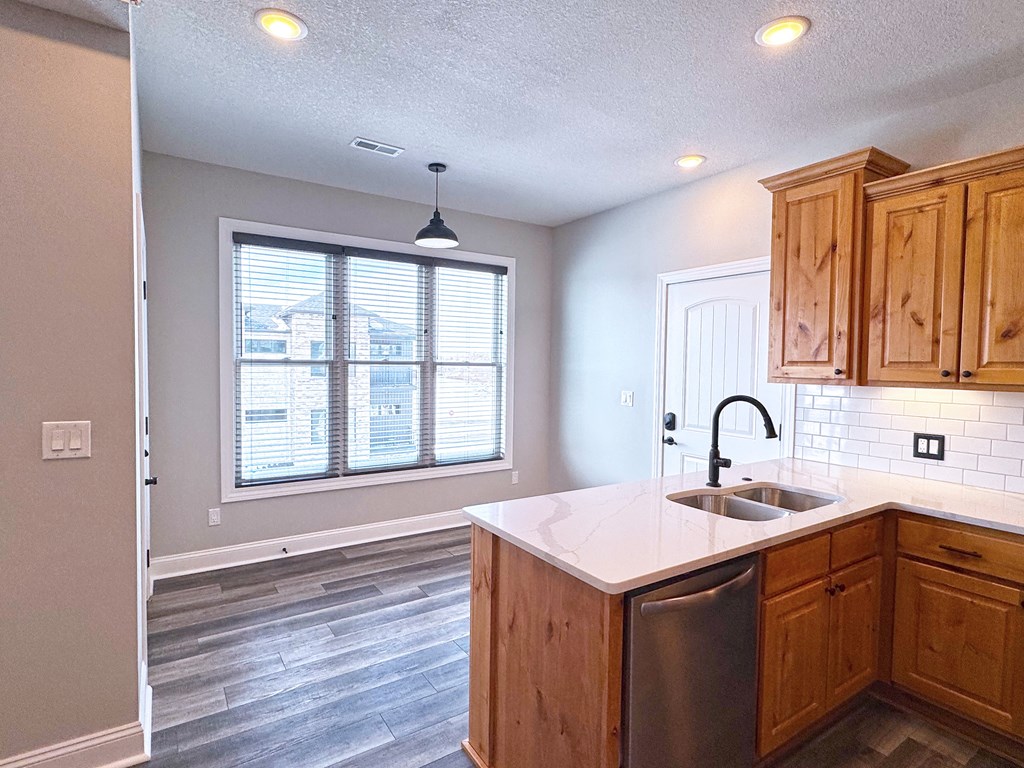 A kitchen with wooden cabinets and a stainless steel dishwasher.