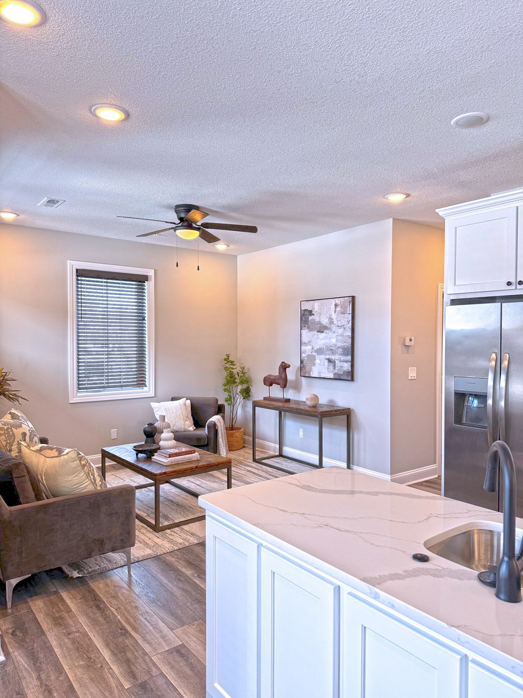 A modern kitchen with a brown sofa and a ceiling fan.