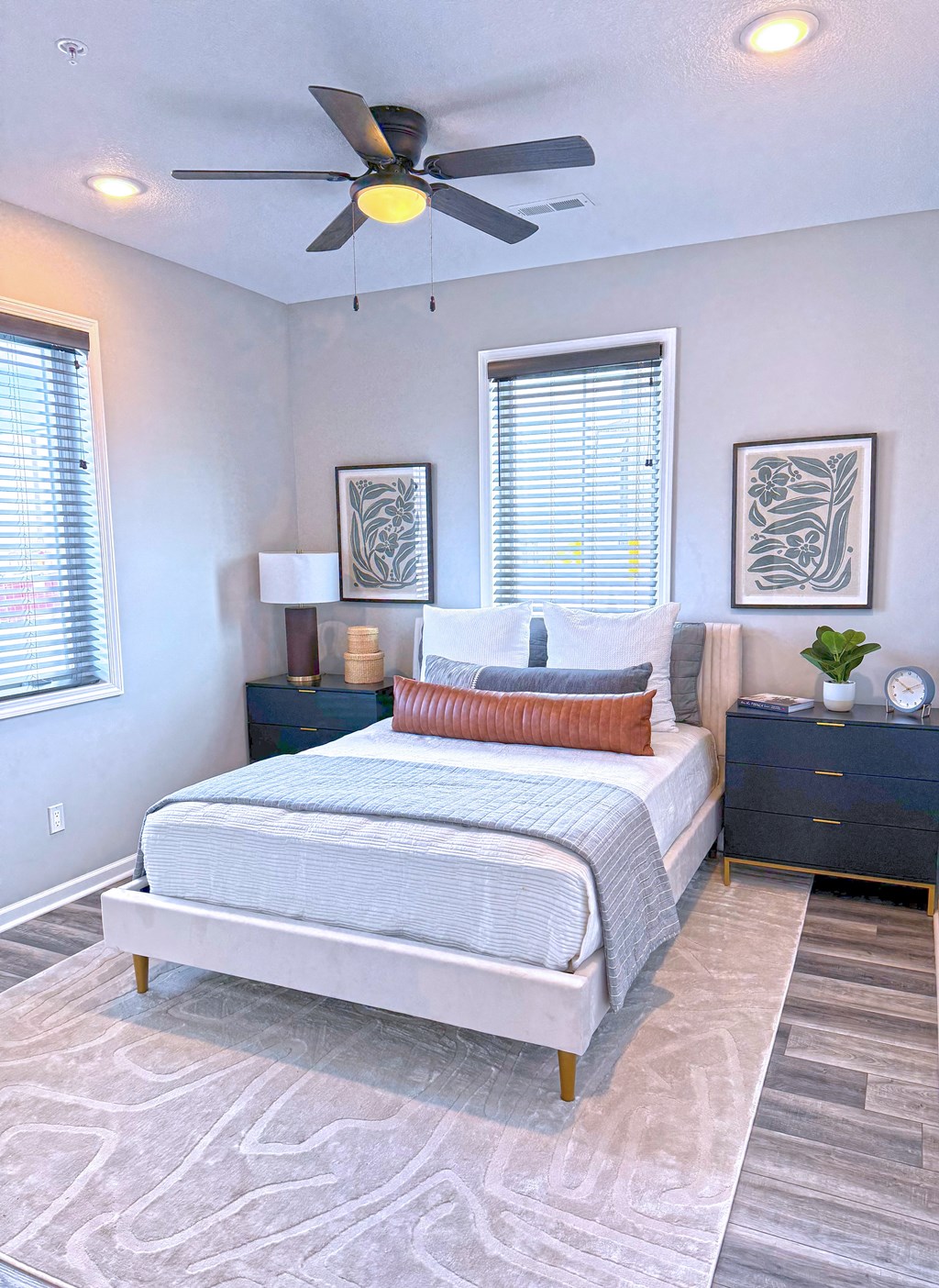 A bedroom with a bed, nightstand, and two framed pictures on the wall.