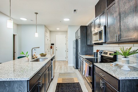 A modern kitchen with dark cabinets and granite countertops.
