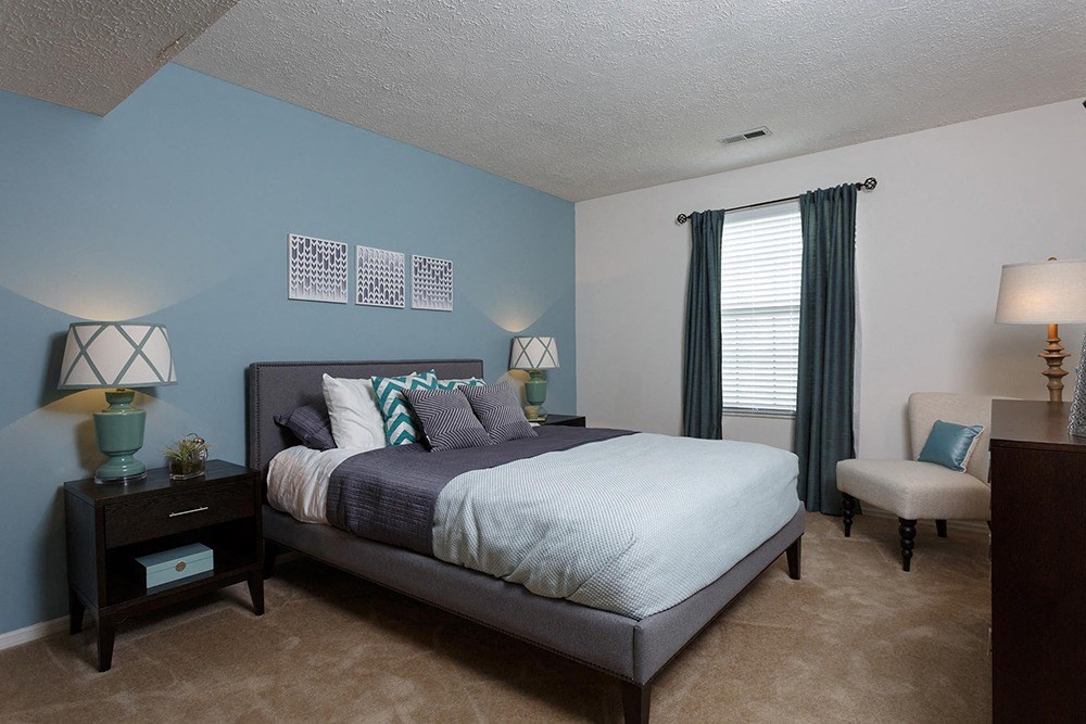 bedroom with window, one light blue wall and gray bed