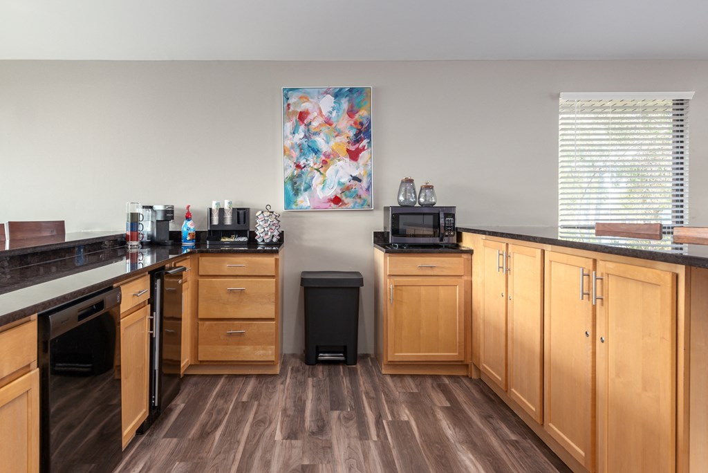 a kitchen with wooden cabinets and a counter top with a sink and a microwave