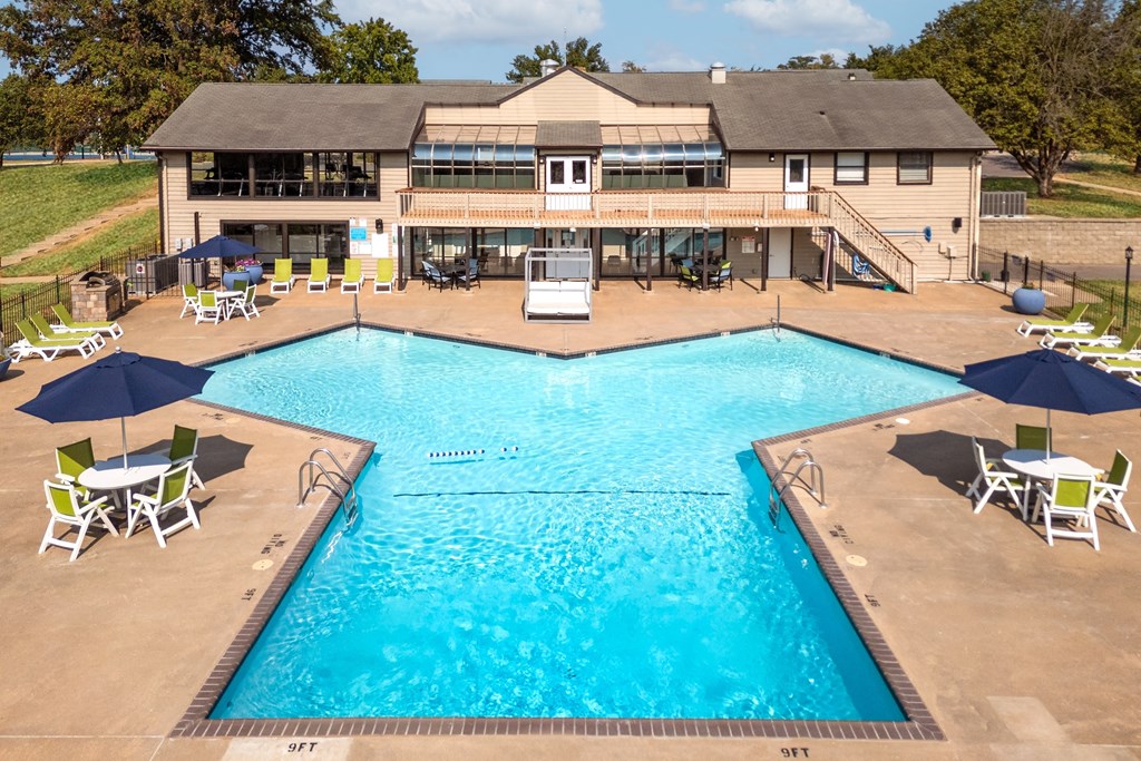 a swimming pool with chairs and umbrellas in front of a resort style pool