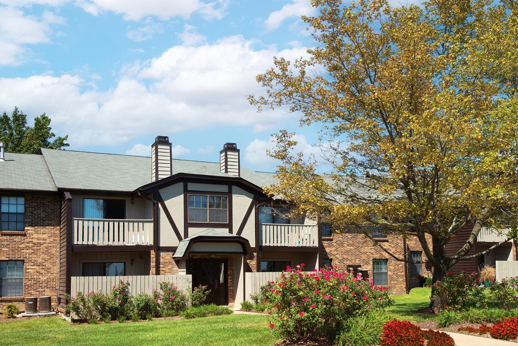 an apartment building with a lawn and flowering plants