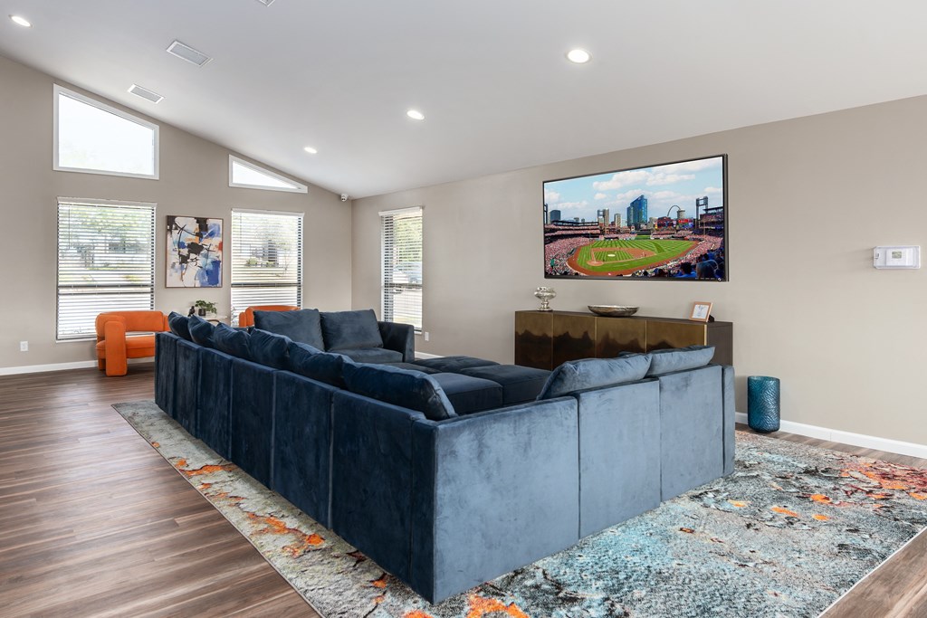 a living room with a blue couch and a tv on the wall