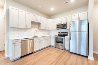 PURE Lowell modern kitchen with white cabinets, stainless steel appliances and plank vinyl flooring