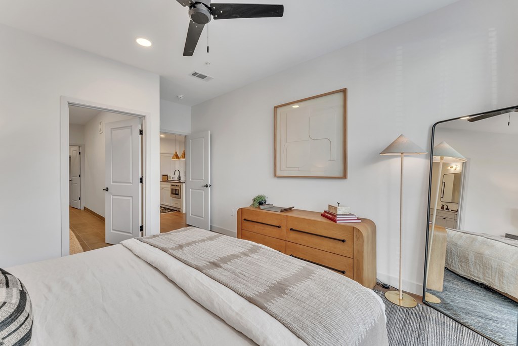A bedroom with a large bed, a dresser, and a mirror.