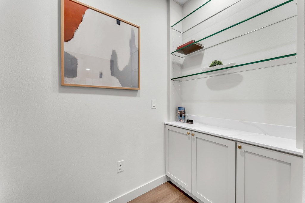 A white cabinet with a painting on the wall above it.