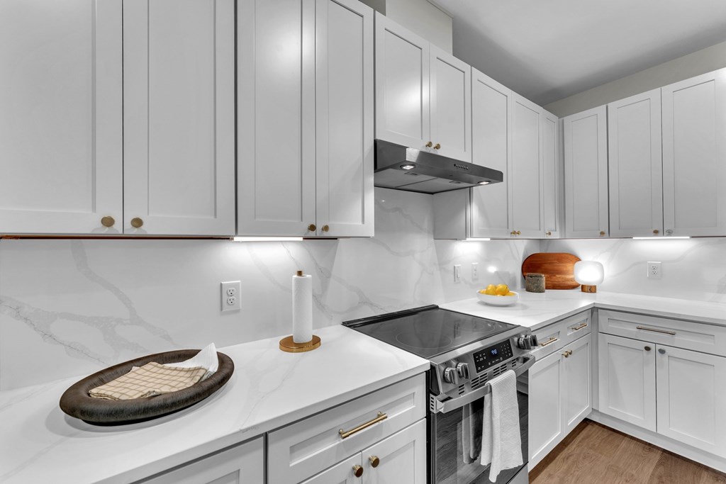 A kitchen with white cabinets and a marble countertop.