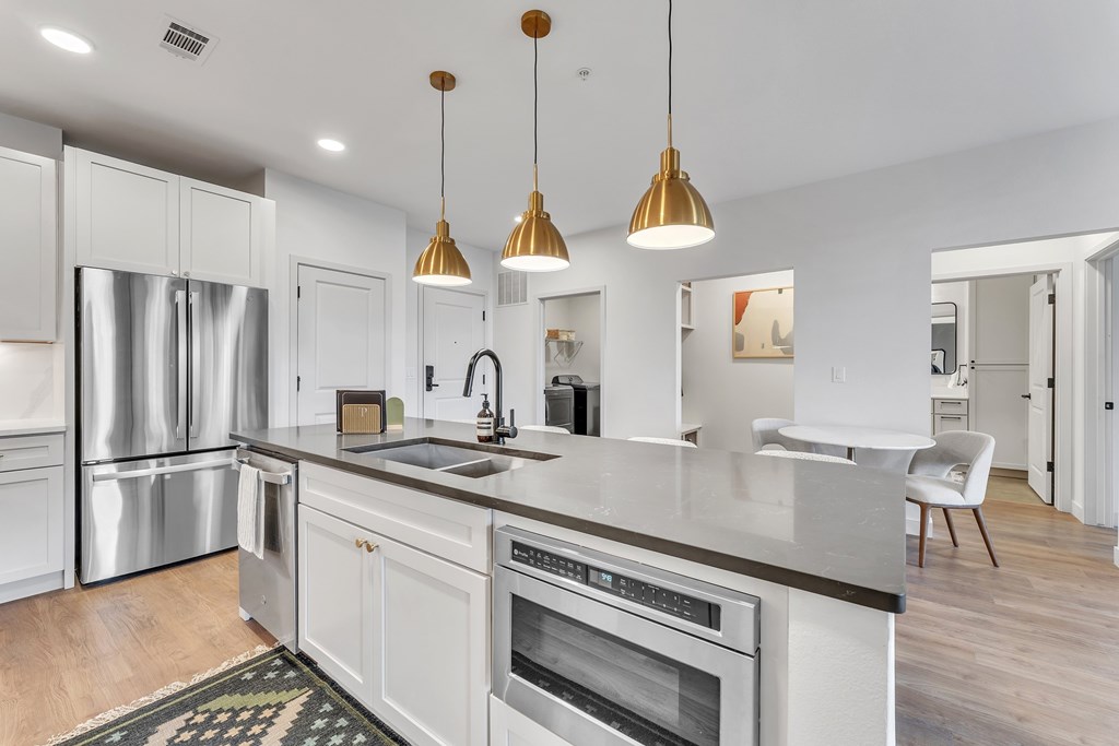 A modern kitchen with a stainless steel refrigerator, a sink, and a stove top oven.