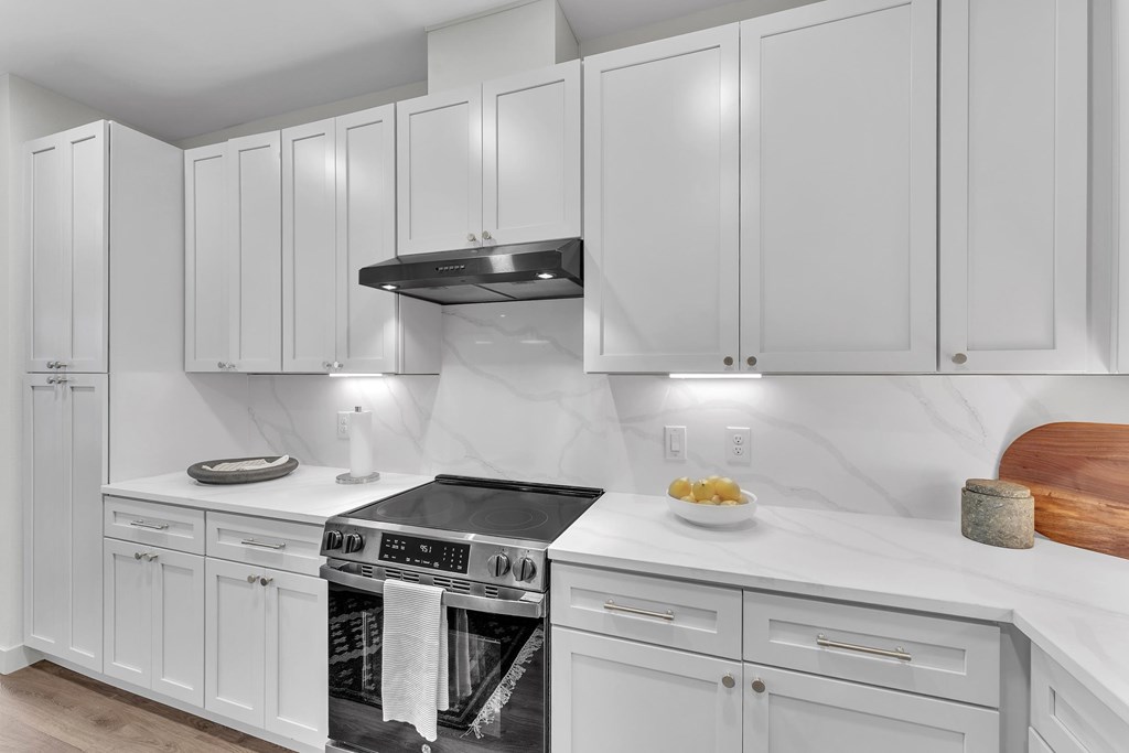 A kitchen with white cabinets and a marble countertop.