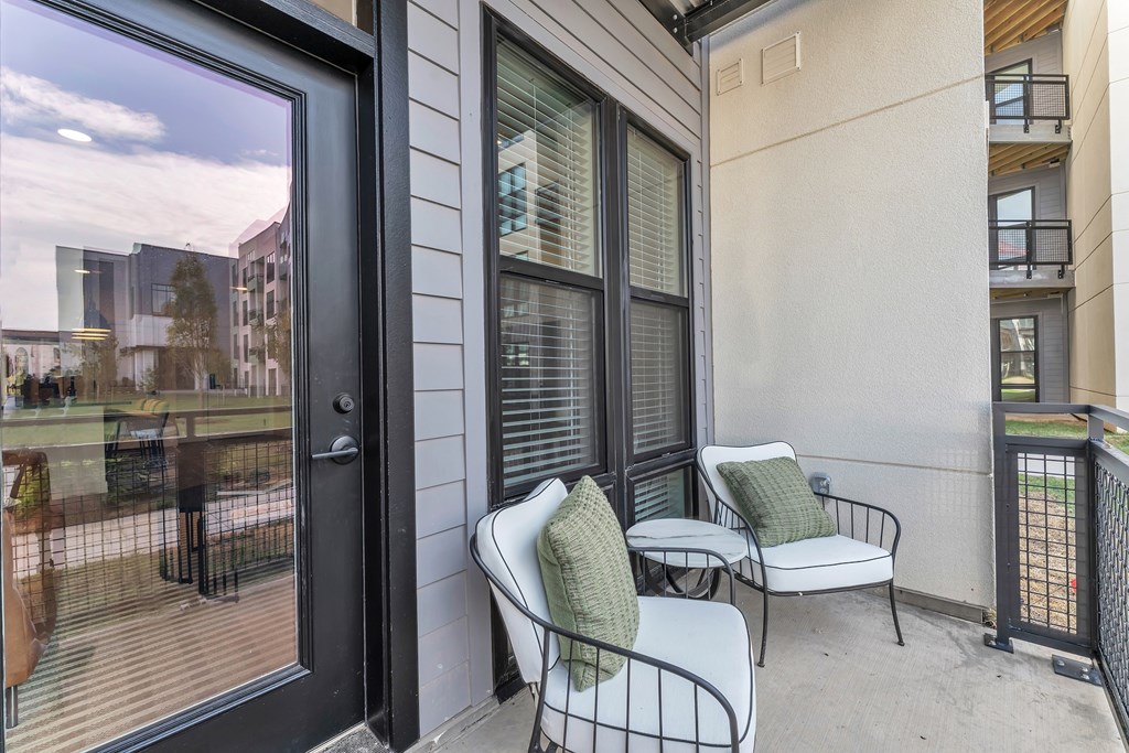 A patio with a chair and a table with a view of the backyards of other houses.