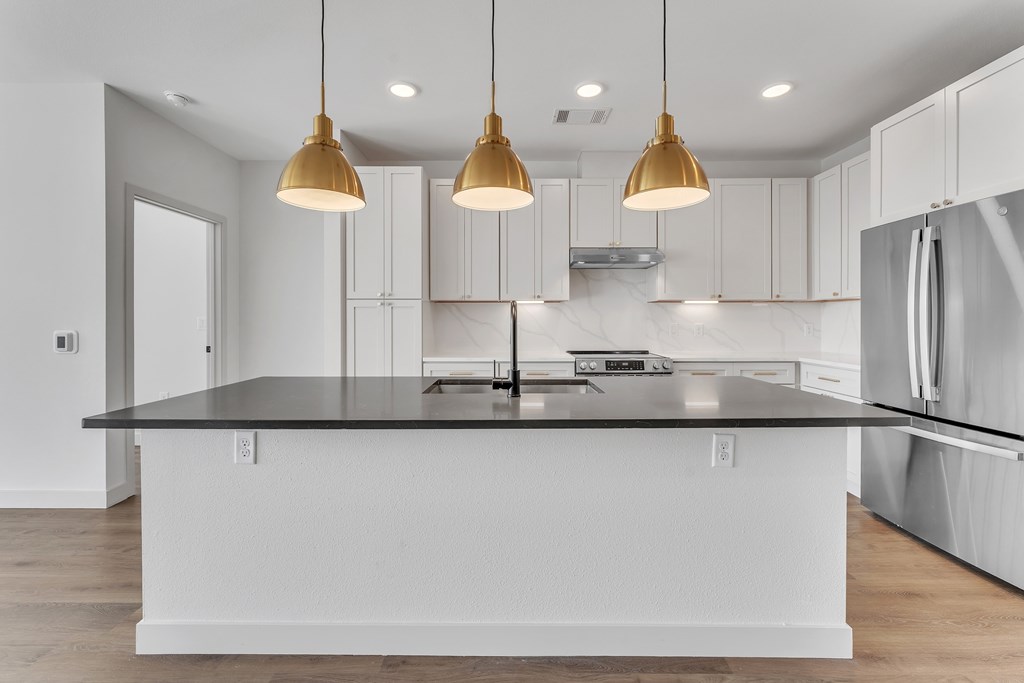 A kitchen with a black countertop and white cabinets.