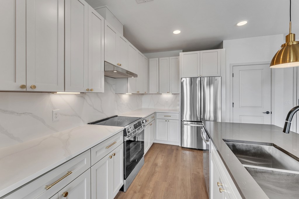 A modern kitchen with white cabinets and stainless steel appliances.