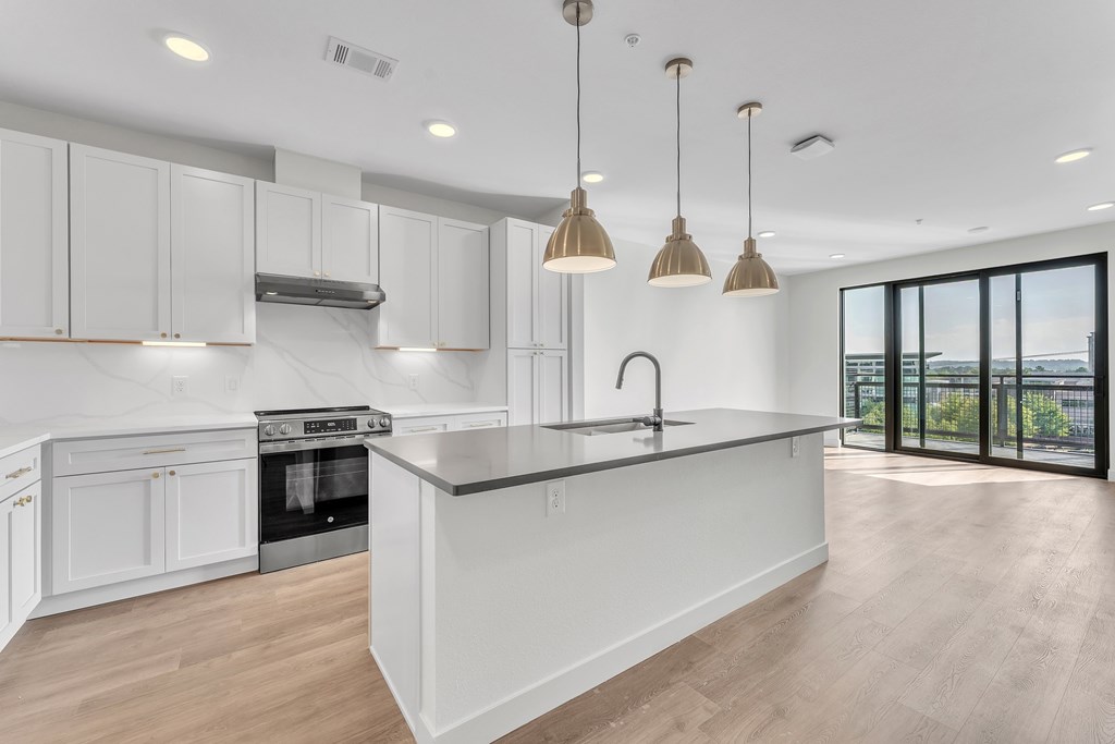 A modern kitchen with white cabinets and a marble island.