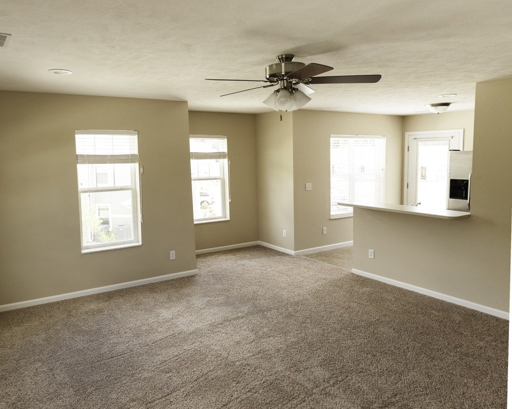 Carpeted Living Room with Ceiling Fan and view of four windows