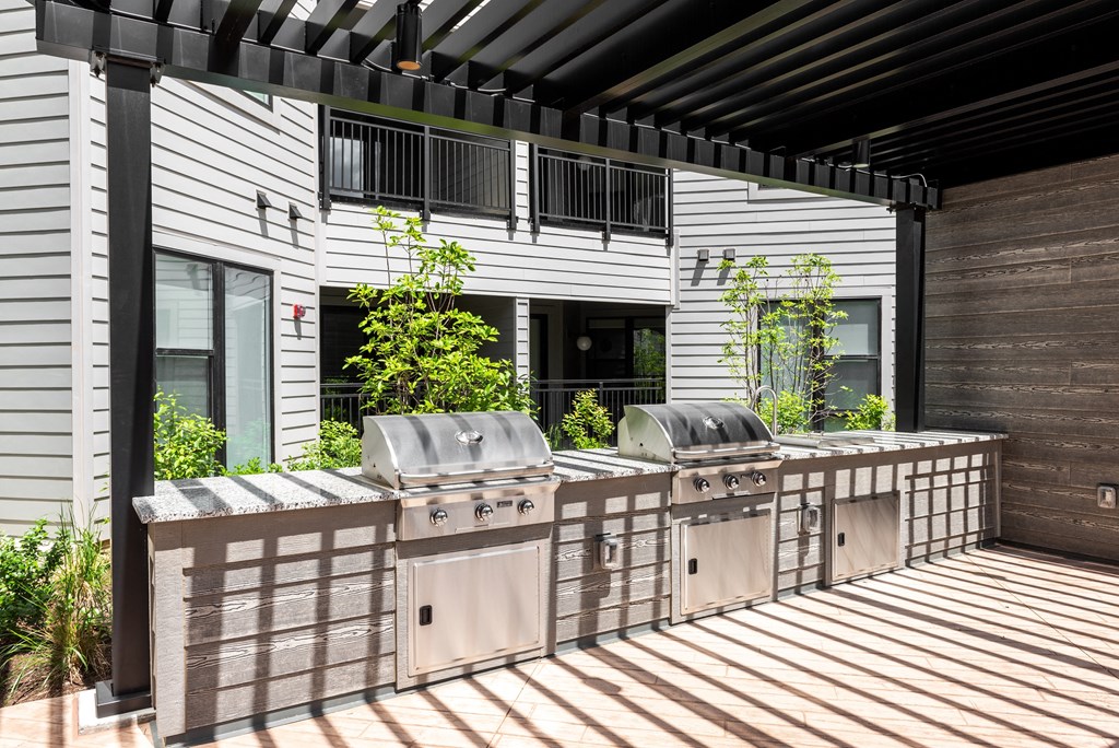 the outdoor kitchen has stainless steel appliances and a bar with grill
