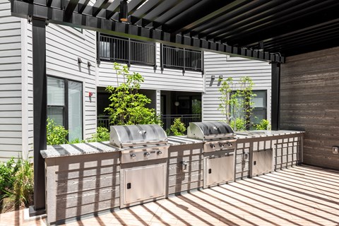 the outdoor kitchen has stainless steel appliances and a bar with grill at The Flats & Terraces at Wildhorse Village, Chesterfield, MO