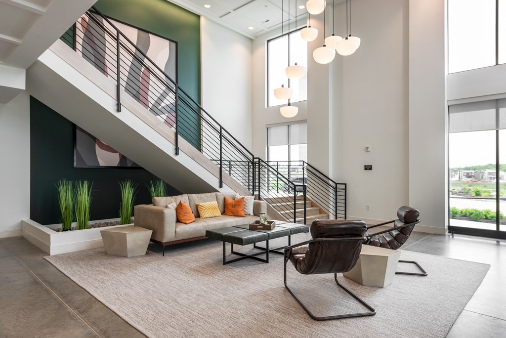 a living room with a couch and a chair in front of a staircase