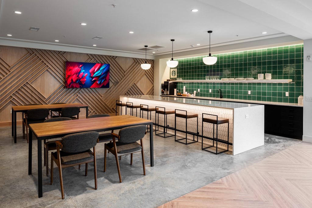 a dining area with a table and chairs and a bar with green tiles