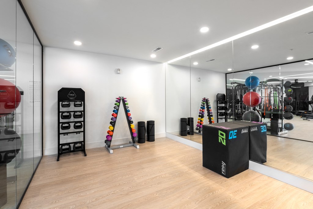 a gym with mirrors and weights on a wooden floor