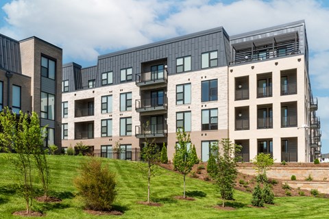 modern apartment buildings on a hill with grass at The Flats & Terraces at Wildhorse Village, Chesterfield, MO