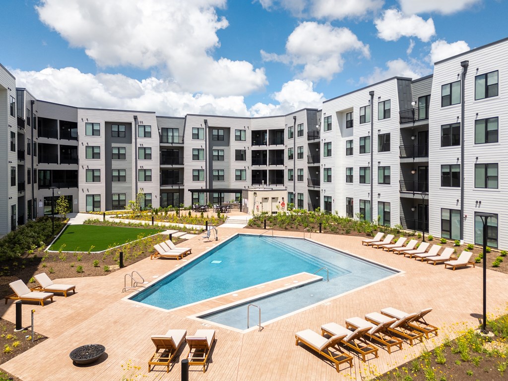 an apartment building with a pool and lounge chairs