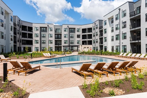 an apartment building with a pool and lounge chairs at The Flats & Terraces at Wildhorse Village, Missouri, 63005
