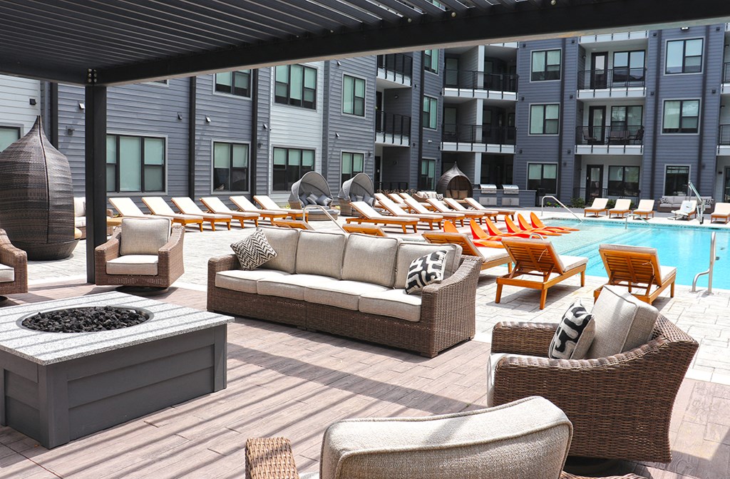 a pool area with lounge chairs and a fire pit